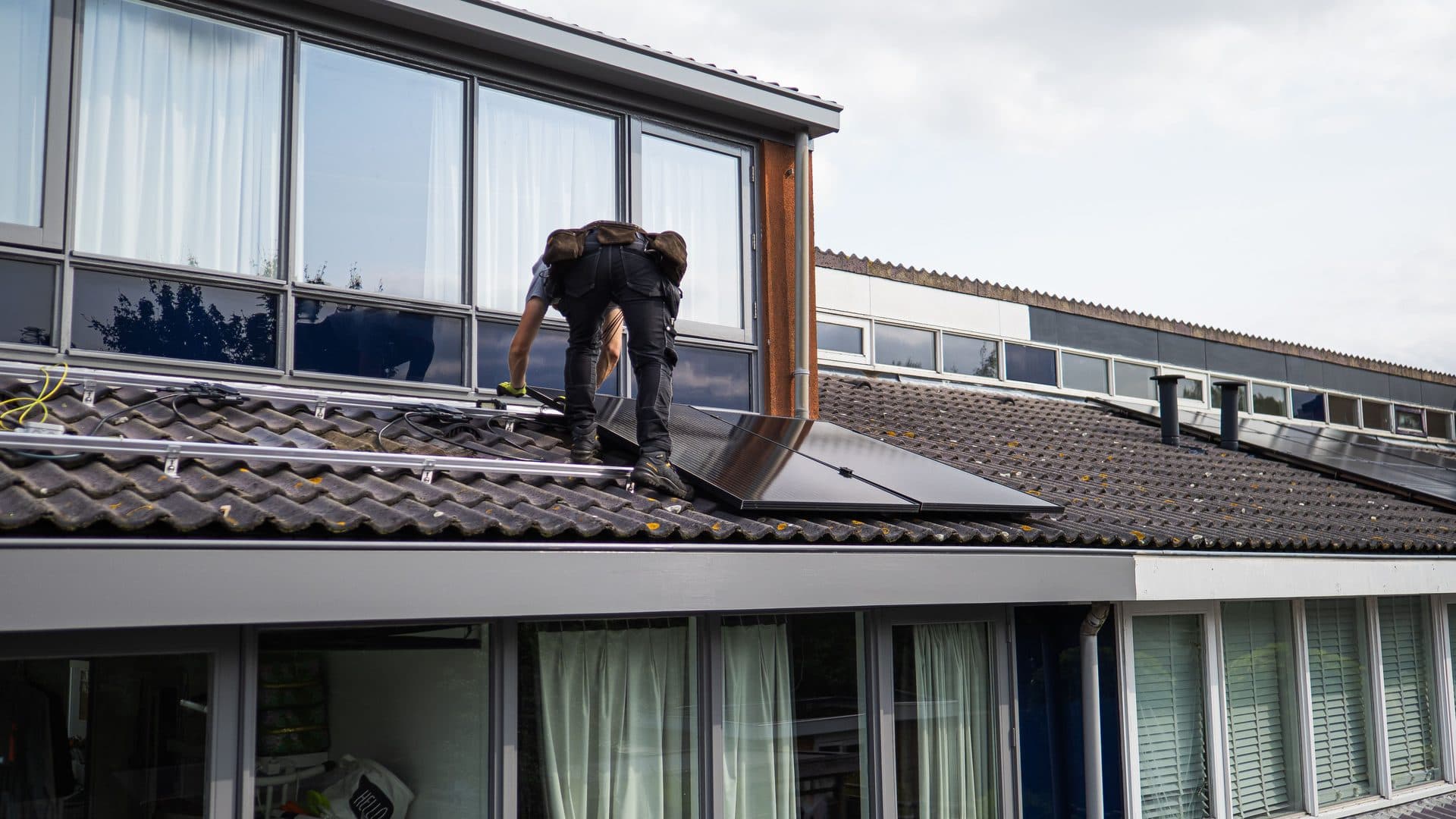 Technician working among solar panels on a residential tile roof
