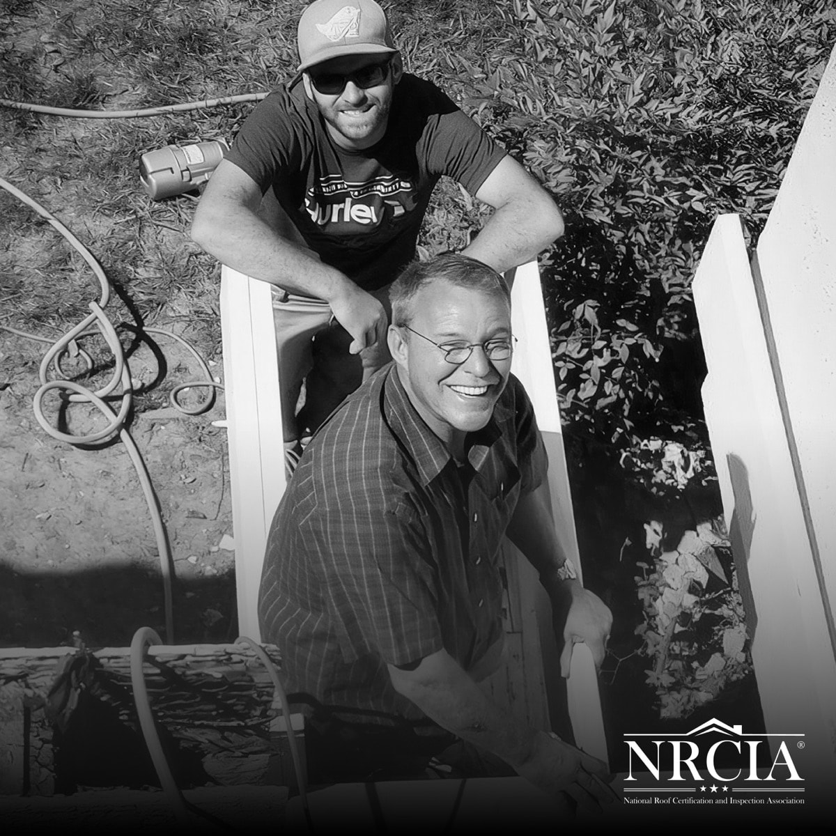 Two men working together beside a deck rail on a job site.