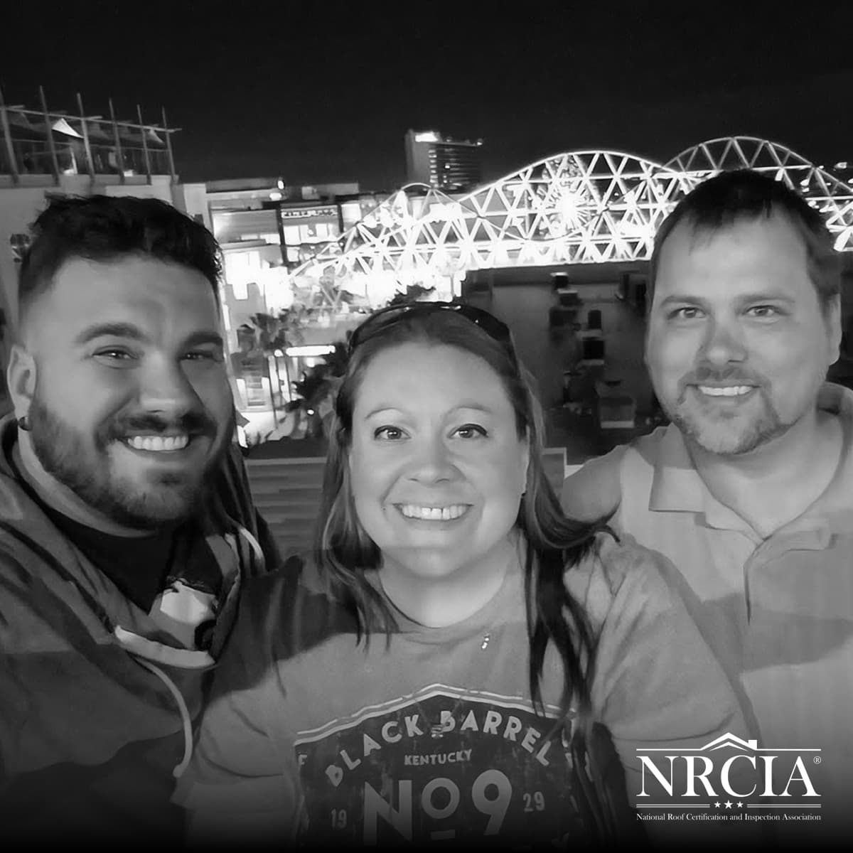 Three people photographed together outdoors in the evening.