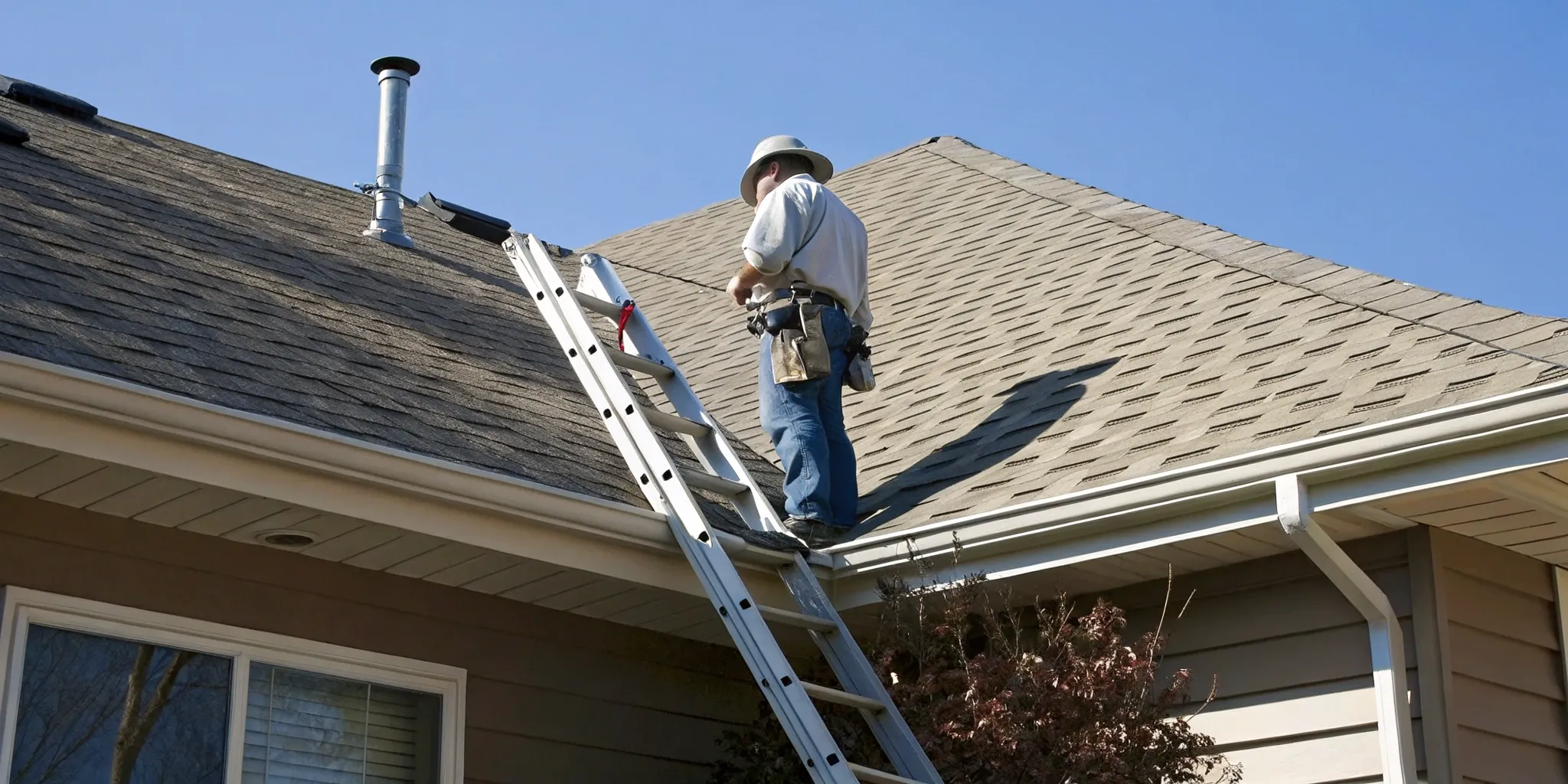 A roofer examines shingles by hand during a roof certification inspection.