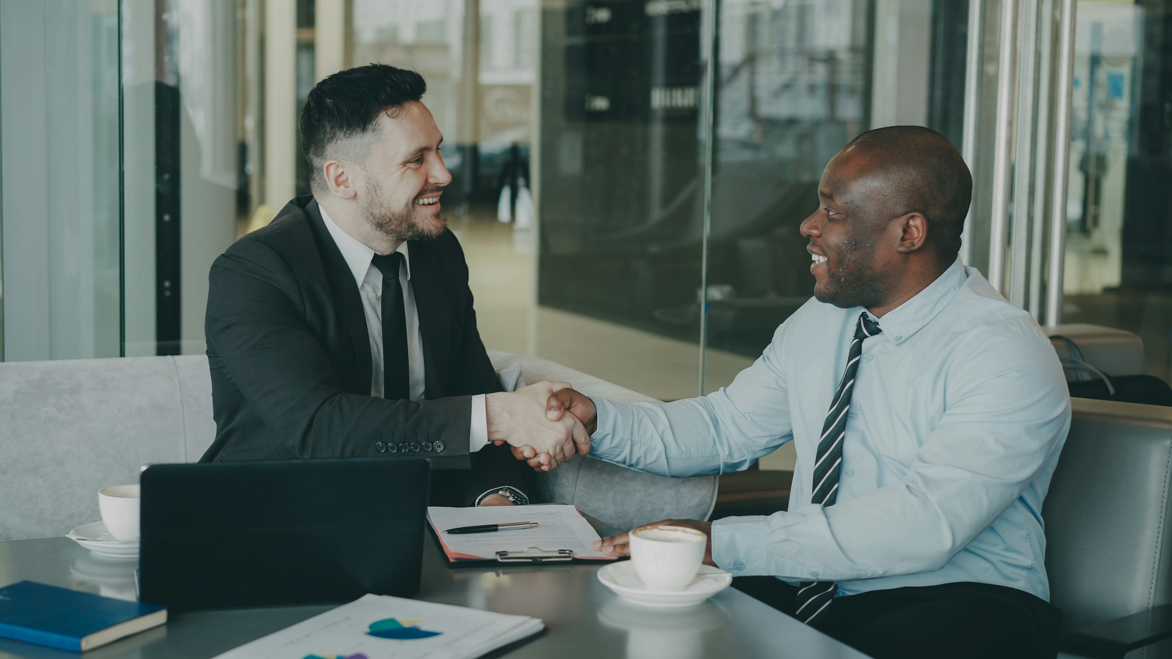 Two people shaking hands across a meeting table