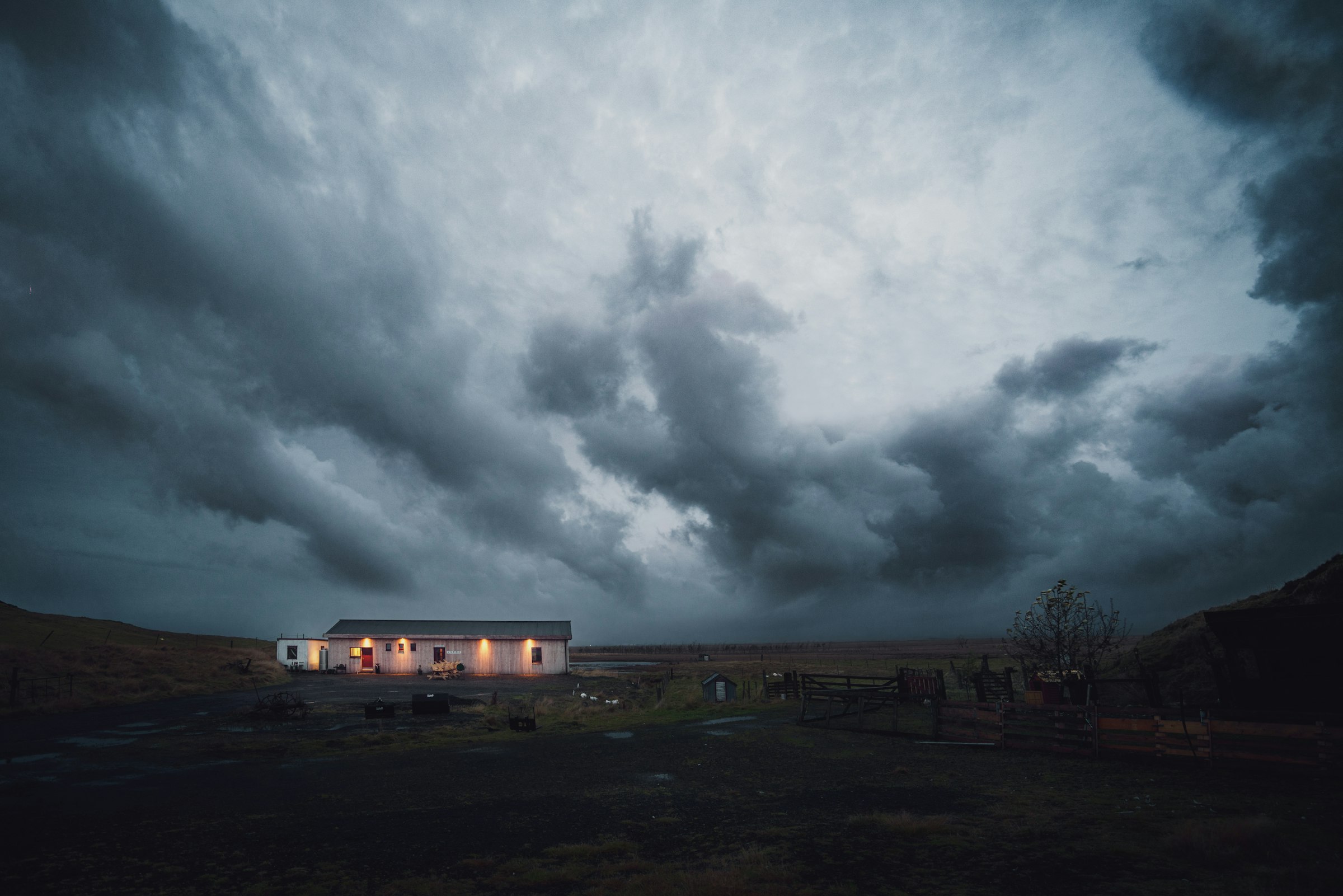 Storm clouds gathering over a house with its lights on